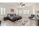 Main bedroom features a dark wood bed frame, light hardwood floors, and large windows at 6299 S Roanoke St, Gilbert, AZ 85298