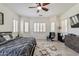 Well-lit bedroom with wood-look floors, ceiling fan, shuttered windows, and a cozy chair with throw at 6299 S Roanoke St, Gilbert, AZ 85298