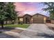 Charming single-story home featuring a stone facade, well-manicured lawn, and a two-car garage at dusk at 6299 S Roanoke St, Gilbert, AZ 85298