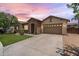 Beautiful single-story home with stone accents, a well-kept lawn, and a two-car garage in the evening at 6299 S Roanoke St, Gilbert, AZ 85298