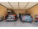 Two-car garage with overhead storage and two parked cars at 6299 S Roanoke St, Gilbert, AZ 85298