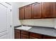 Laundry room with dark wood cabinets, gray countertop, and a white utility sink at 6299 S Roanoke St, Gilbert, AZ 85298