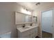 Bathroom with double sinks and bright lighting, complemented by an adjacent walk in closet and white walls at 6434 W Riva Rd, Phoenix, AZ 85043