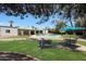 Expansive backyard featuring a pool, green grass, palm trees and shaded dining area with an umbrella at 6911 E Thunderbird Rd, Scottsdale, AZ 85254