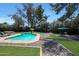 This backyard features a pool, seating area, mature shade trees, and grass at 6911 E Thunderbird Rd, Scottsdale, AZ 85254