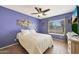 Blue bedroom with wood-look floors, ceiling fan, window view, and accent wall decor at 6911 E Thunderbird Rd, Scottsdale, AZ 85254