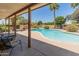 An inviting covered patio looks out to a pool with mature landscaping and an outdoor fireplace in this backyard at 6931 E Pershing Ave, Scottsdale, AZ 85254
