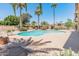 A large kidney-shaped pool is surrounded by mature landscaping, palm trees, and a desert rockscape at 6931 E Pershing Ave, Scottsdale, AZ 85254