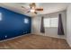 Bedroom features carpeted floors, a fan, two windows, a dark blue accent wall and neutral colored walls at 9 S 195Th Ln, Buckeye, AZ 85326