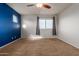 Bedroom features carpeted floors, a fan, two windows, a dark blue accent wall and neutral colored walls at 9 S 195Th Ln, Buckeye, AZ 85326