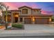 Inviting two-story desert home showcasing an arched entry, three-car garage, desert landscaping, and sunset sky at 11124 N 138Th Way, Scottsdale, AZ 85259