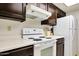 Cozy kitchen features a white electric range and hood, with dark cabinets and a white refrigerator at 1122 E Michelle Dr, Phoenix, AZ 85022