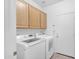 Bright laundry room with white washer, dryer and natural wood cabinets above at 12605 E Kalil Dr, Scottsdale, AZ 85259