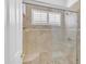 Elegant shower with glass door, neutral tiling, a built-in bench, and a window with white shutters at 12605 E Kalil Dr, Scottsdale, AZ 85259