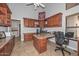Home office featuring custom wood cabinetry, a built-in desk, and multiple workstations with neutral tile flooring at 1623 E Runion Dr, Phoenix, AZ 85024