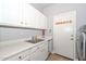 Laundry room with utility sink, white cabinets, and convenient access to the door at 1623 E Runion Dr, Phoenix, AZ 85024