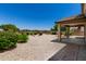 Backyard with a covered patio, mature plants, and gravel landscaping for low maintenance at 16450 W Lilac St, Goodyear, AZ 85338