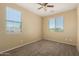 Bedroom featuring neutral walls, carpet, ceiling fan, and two windows with views at 16450 W Lilac St, Goodyear, AZ 85338