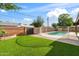 Beautiful backyard features a fenced in pool area, well manicured grass, and landscaped features at 1713 W Royal Palm Rd, Phoenix, AZ 85021