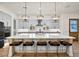 Bright kitchen with a large island featuring modern pendant lighting, bar seating, and a view of sleek appliances at 17146 W Mountainair St, Surprise, AZ 85388