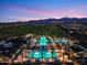 Beautiful night shot of a community pool, framed by palm trees and backed by scenic mountains and a dusky sky at 17146 W Mountainair St, Surprise, AZ 85388