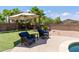 Backyard lounge area with an umbrella, chairs, and table at 18432 W Port Royale Ln, Surprise, AZ 85388