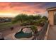 A stunning sunset view overlooking a beautiful backyard pool with lush landscaping, perfect for tranquil evenings at 18432 W Port Royale Ln, Surprise, AZ 85388