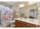 Bathroom featuring double sinks, large mirror, toilet, and shower with floral curtain at 18432 W Port Royale Ln, Surprise, AZ 85388