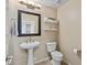 Powder room features a pedestal sink, toilet, and decorative shelving at 18432 W Port Royale Ln, Surprise, AZ 85388