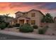 Exterior view of a two-story home with a three-car garage and well-manicured landscaping at 18432 W Port Royale Ln, Surprise, AZ 85388