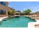 This backyard features a large in-ground pool with an umbrella, rock waterfall feature, and lounge chairs at 18432 W Port Royale Ln, Surprise, AZ 85388