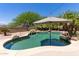 This backyard features an in-ground pool with umbrella, and a rock feature at 18432 W Port Royale Ln, Surprise, AZ 85388
