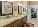 Bathroom featuring dual sinks with granite countertops, framed mirrors, and a view to the walk-in closet at 18634 N Paloma Ct, Surprise, AZ 85387