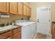 Bright laundry room boasts wood cabinets, wash basin, a modern washer and dryer, and easy access to the home's exterior at 18634 N Paloma Ct, Surprise, AZ 85387