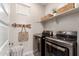 Modern laundry room with gray front-load machines, white shelving, and a decorative hook rack at 1882 S Jesse Pl, Chandler, AZ 85286