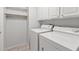 A well-lit laundry room with white appliances and overhead cabinets and shelving at 19530 N 84Th Ave, Peoria, AZ 85382