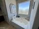 Bathroom featuring a large tub, a decorative mirror, and a view of the sky through the window at 21873 W Pima St, Buckeye, AZ 85326