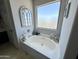 Bathroom featuring a large tub, a decorative mirror, and a view of the sky through the window at 21873 W Pima St, Buckeye, AZ 85326