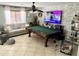 This room features a green pool table, neutral couch and decor, ceiling fan, and a large flatscreen television at 21873 W Pima St, Buckeye, AZ 85326