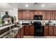 A modern kitchen showcasing granite countertops, stainless steel sink, and wood cabinetry at 2223 S Hughes Dr, Buckeye, AZ 85326