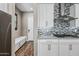 The kitchen boasts white cabinets, a stainless range hood, and a backsplash, with a bench near the entry door at 2315 W Duane Ln, Phoenix, AZ 85085
