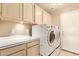 Bright laundry room features side-by-side washer and dryer, countertop and cabinets, and a neutral color palette at 251 E Arabian Dr, Gilbert, AZ 85296