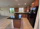 Kitchen with wood cabinets, black appliances, granite countertops, island, and tile flooring at 26747 W Pontiac Dr, Buckeye, AZ 85396