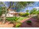 Spacious backyard with lush landscaping, mature trees, green grass, and a covered patio at 3025 N Desert Horizons Ln, Casa Grande, AZ 85122
