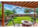 Inviting backyard featuring a covered patio, green lawn, landscaped flower beds, and a charming firepit at 3025 N Desert Horizons Ln, Casa Grande, AZ 85122