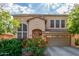 Two-story home with a tan stucco exterior, tile roof, attached garage, and vibrant orange flowering bushes at 3025 N Desert Horizons Ln, Casa Grande, AZ 85122