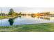 A serene community pond reflecting the sunset, framed by green grass and mature trees for a tranquil ambiance at 3025 N Desert Horizons Ln, Casa Grande, AZ 85122