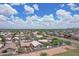 Overview of a sprawling community with well-maintained homes, green spaces, and blue skies with scattered clouds at 3586 S Moccasin Trl, Gilbert, AZ 85297