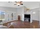 Open living room with hardwood floors, large windows, modern entertainment center, and French door access to backyard at 3586 S Moccasin Trl, Gilbert, AZ 85297