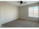 This bedroom features neutral walls, carpet, a ceiling fan, and a window for natural light at 3840 N 43Rd Ave # 34, Phoenix, AZ 85031